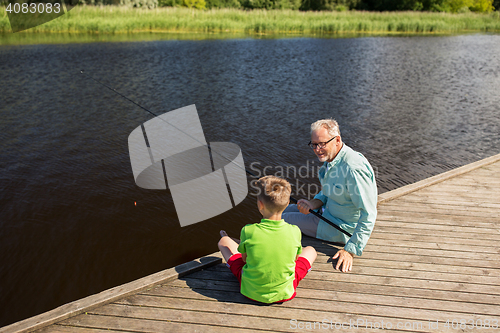 Image of grandfather and grandson fishing on river berth