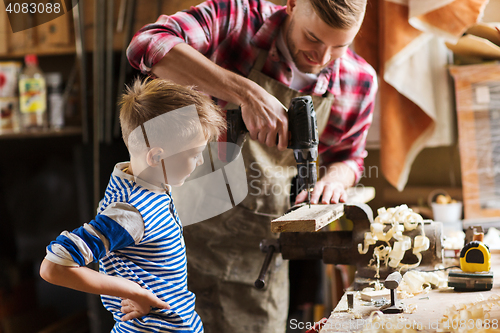 Image of father and son with drill working at workshop