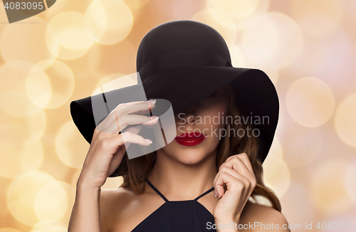 Image of beautiful woman in black hat over holidays lights