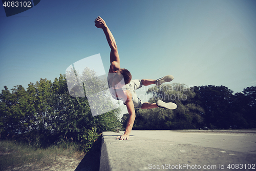 Image of sporty young man jumping in summer park