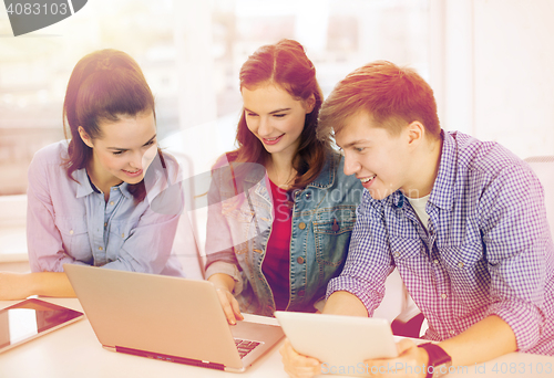 Image of three smiling students with laptop and tablet pc