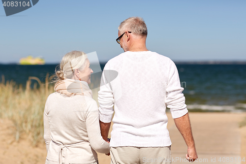 Image of happy senior couple holding hands on summer beach