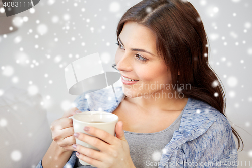 Image of happy woman with cup of tea at home