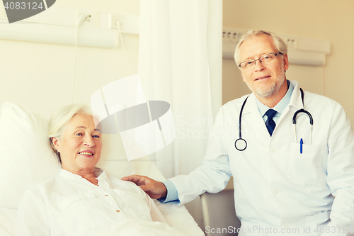 Image of doctor visiting senior woman at hospital ward