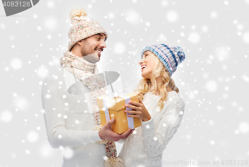 Image of smiling couple in winter clothes with gift box