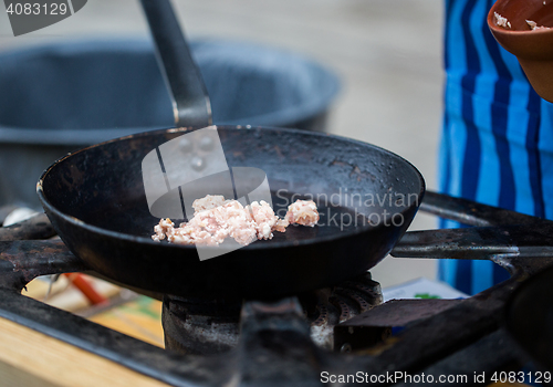 Image of forcemeat on frying pan at street market