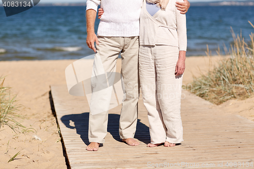Image of close up of senior couple hugging on summer beach
