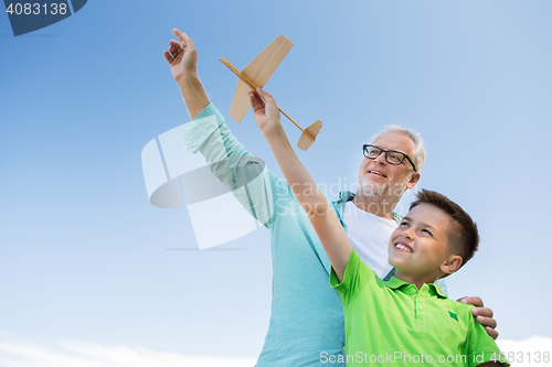 Image of senior man and boy with toy airplane over sky