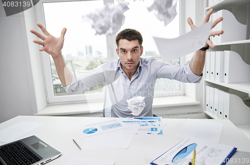 Image of angry businessman throwing papers in office