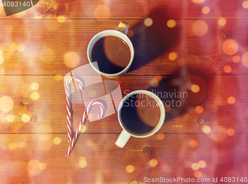 Image of christmas candy canes and cups on wooden table