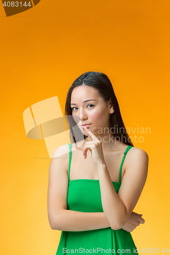 Image of The thinking Chinese girl on yellow background