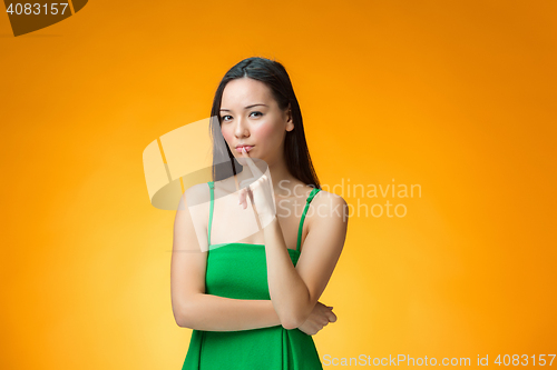 Image of The thinking Chinese girl on yellow background