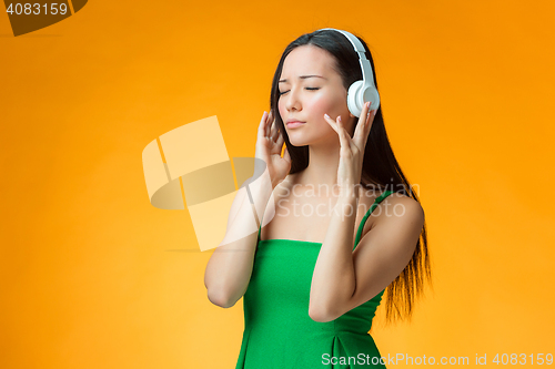 Image of The cute cheerful girl on orange background