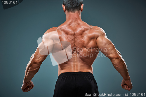 Image of torso of attractive male body builder on gray background.