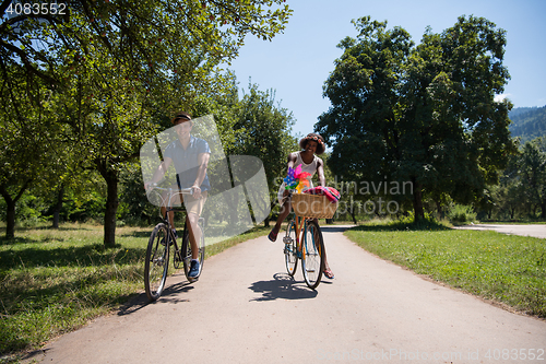 Image of Young multiethnic couple having a bike ride in nature