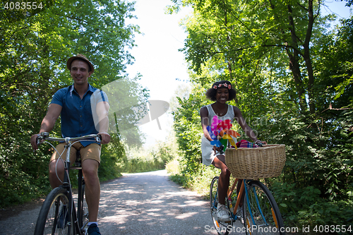 Image of Young multiethnic couple having a bike ride in nature