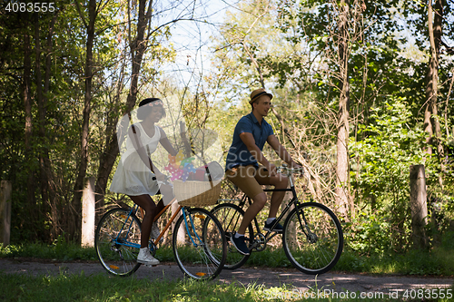 Image of Young multiethnic couple having a bike ride in nature
