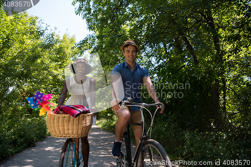 Image of Young multiethnic couple having a bike ride in nature