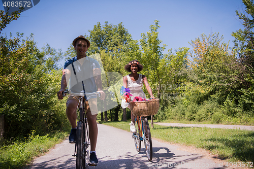 Image of Young multiethnic couple having a bike ride in nature