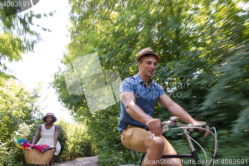 Image of Young multiethnic couple having a bike ride in nature