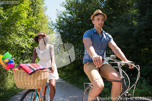 Image of Young multiethnic couple having a bike ride in nature