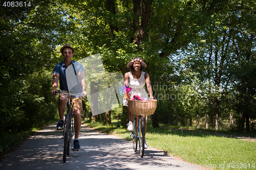 Image of Young multiethnic couple having a bike ride in nature