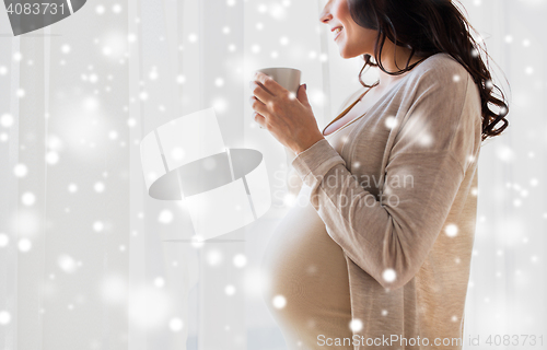 Image of close up of pregnant woman with tea cup at window