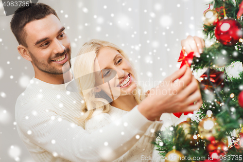 Image of happy couple decorating christmas tree at home