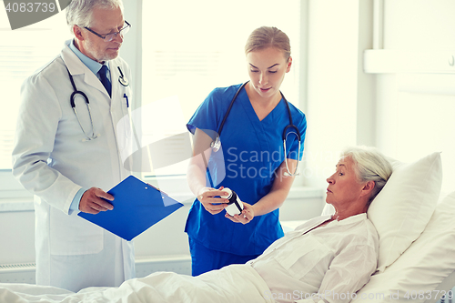 Image of doctor giving medicine to senior woman at hospital