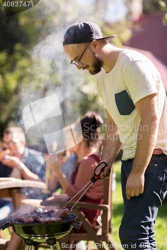 Image of man cooking meat on barbecue grill at summer party