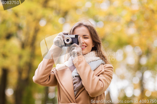 Image of woman photographing with camera in autumn park