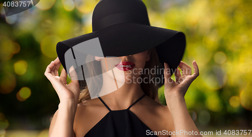 Image of beautiful woman in black hat over dark background