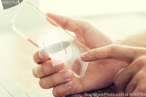 Image of close up of male hand with transparent smartphone