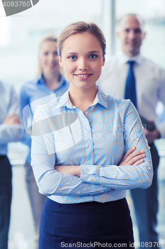 Image of smiling businesswoman with colleagues in office
