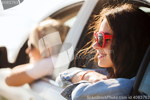 Image of happy teenage girls or women in car at seaside