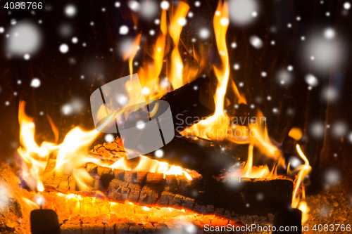 Image of close up of firewood burning in fireplace and snow