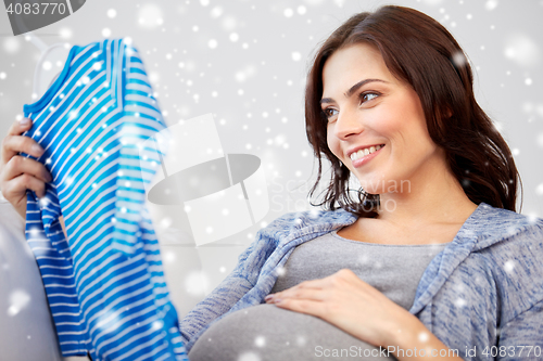 Image of happy woman holding baby boys bodysuit at home