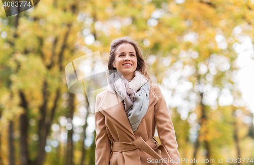 Image of beautiful happy young woman walking in autumn park