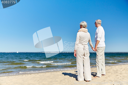 Image of happy senior couple holding hands summer beach