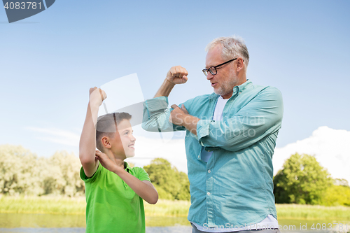 Image of happy grandfather and grandson showing muscles