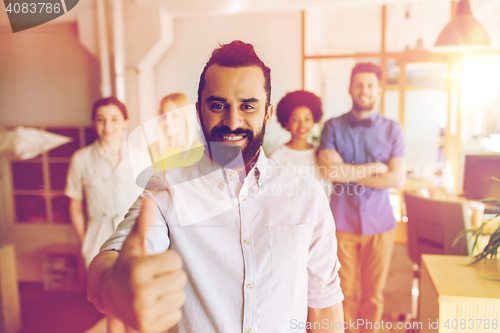 Image of happy creative team showing thumbs up in office