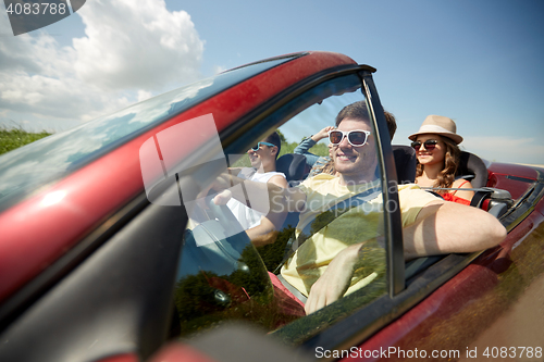 Image of happy friends driving in cabriolet car