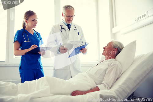 Image of doctor and nurse visiting senior woman at hospital