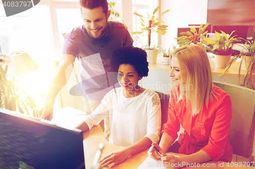 Image of happy creative team with computer in office