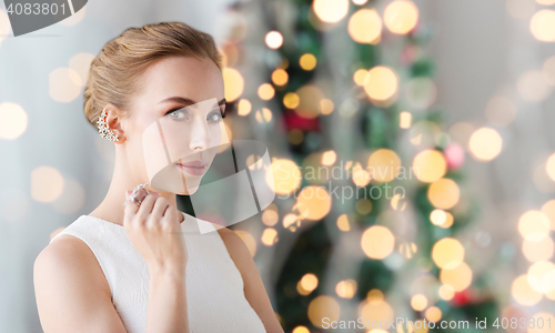 Image of woman with diamond jewelry over christmas lights