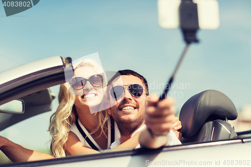 Image of happy couple in car taking selfie with smartphone