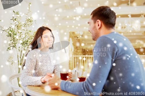 Image of happy couple with tea holding hands at restaurant