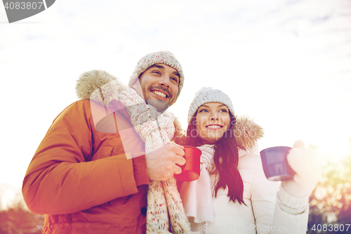 Image of happy couple with tea cups over winter landscape