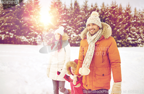Image of happy family in winter clothes walking outdoors