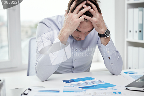 Image of stressed businessman with papers in office